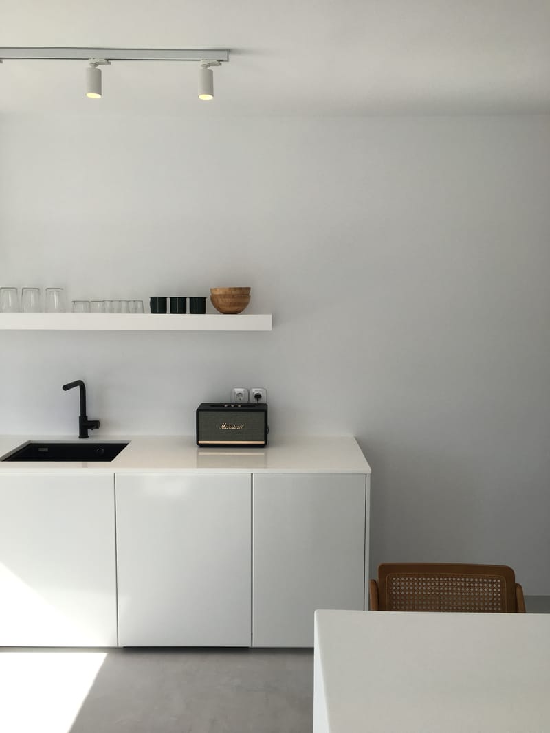 Kitchenette with track lights, open shelf and a rattan chair
