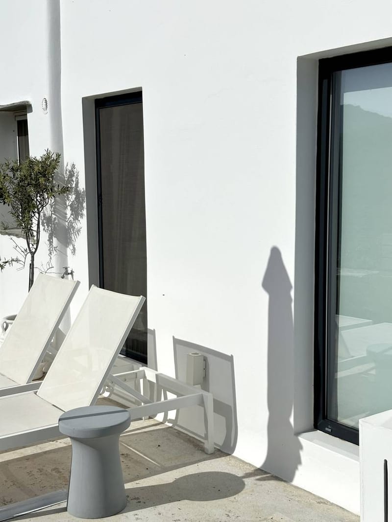 Ξαπλώστρες και ένα γκρι σκαμπό μπροστά στο λευκό σπίτι